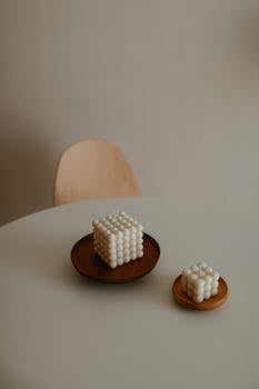 Elegant minimalist setup of cube candles on round table with wooden platters.