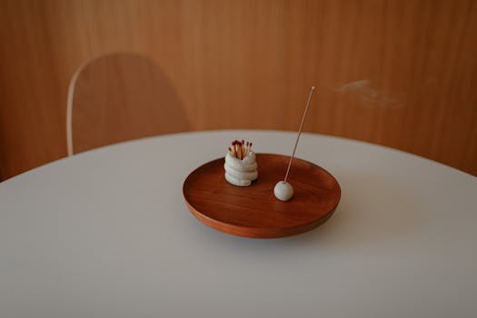 Simple still life featuring incense smoke and matches on a wooden plate.