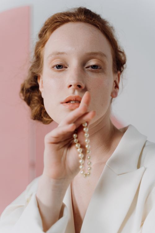 Free Close-up of an elegant woman holding a pearl necklace, exuding sophistication and grace. Stock Photo