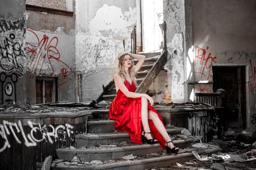 Free A model in a red dress poses in an abandoned, graffiti-filled building. Stock Photo