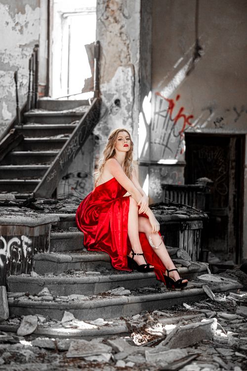 Free Model in a red gown poses glamorously in a derelict building. Stock Photo