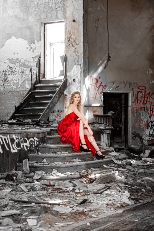 Free A woman in a red gown poses elegantly amid the ruins of an abandoned building, creating a striking contrast. Stock Photo