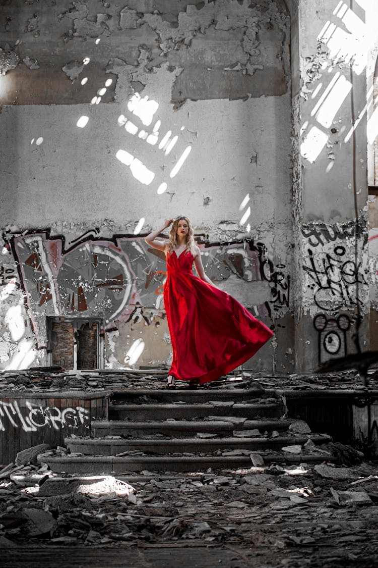 A Woman In Red Dress Standing On The Stage Of An Abandoned Building