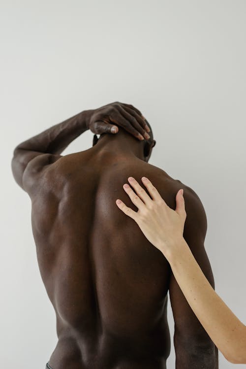 A Shirtless Man Standing with his Back Toward the Camera