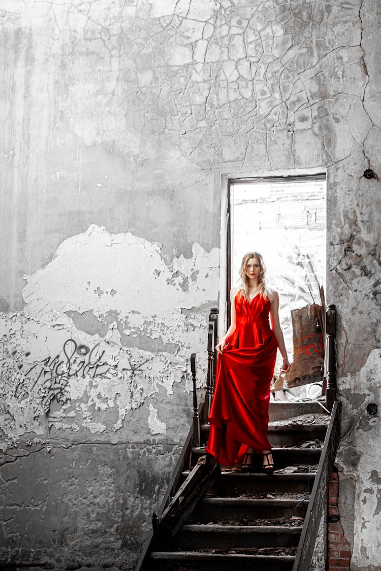 A Woman In Red Dress Standing On The Stairs Of An Old Building