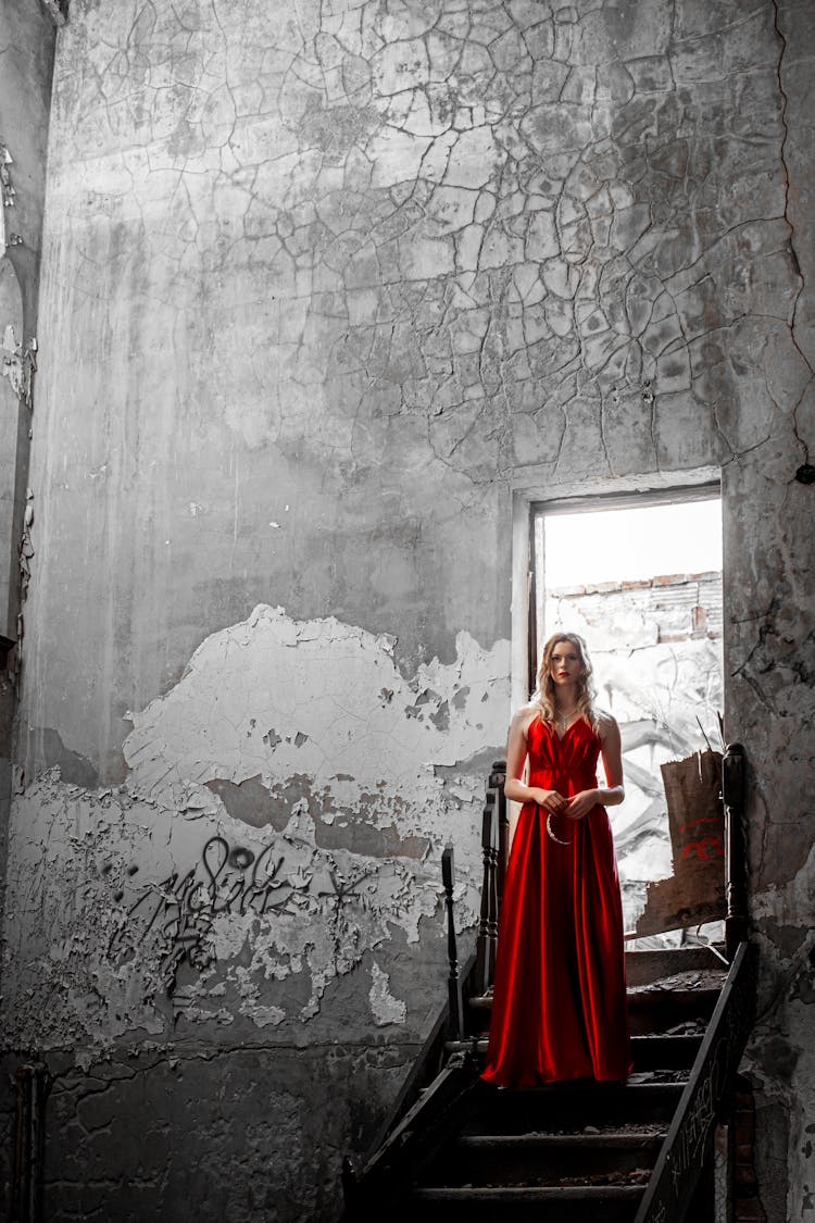 A Woman In Red Dress Standing On The Stairs Of An Old Building