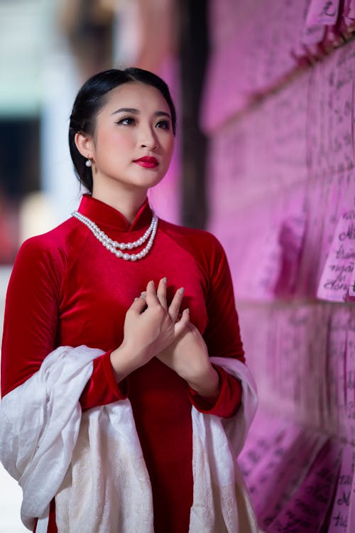 Free Elegant young ethnic woman with red lips standing near prayer papers wall Stock Photo