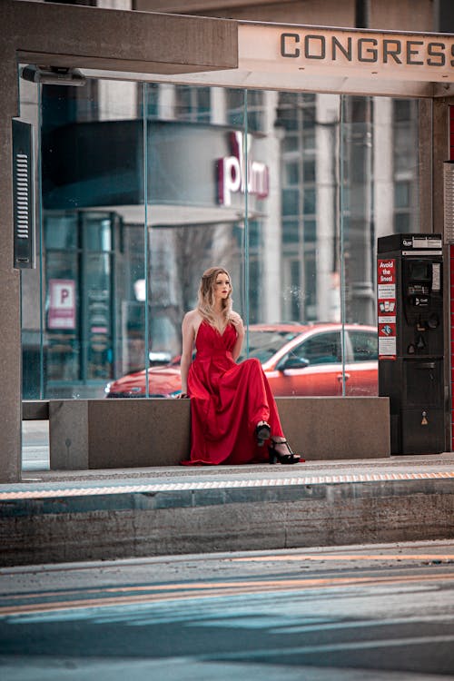 Woman in a Red Dress Waiting at a Bus Stop