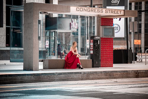 
A Woman Wearing a Red Dress in a Bus Stop