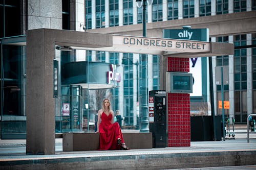 
A Woman Wearing a Red Dress in a Bus Stop