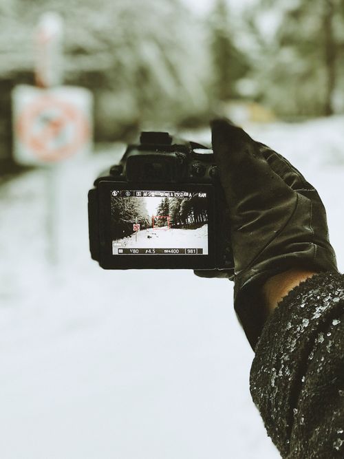 Free A gloved hand holding a camera capturing a snowy wintry landscape view in County Dublin, Ireland. Stock Photo