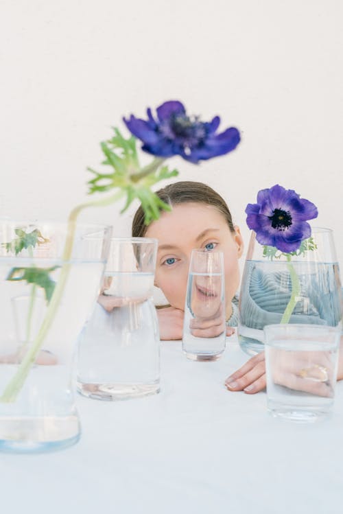 Free Young Woman Behind Bottles with Flowers  Stock Photo