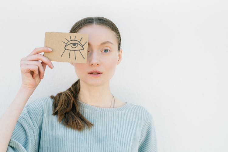 A Woman Holding A Cardboard With An Eye Drawing