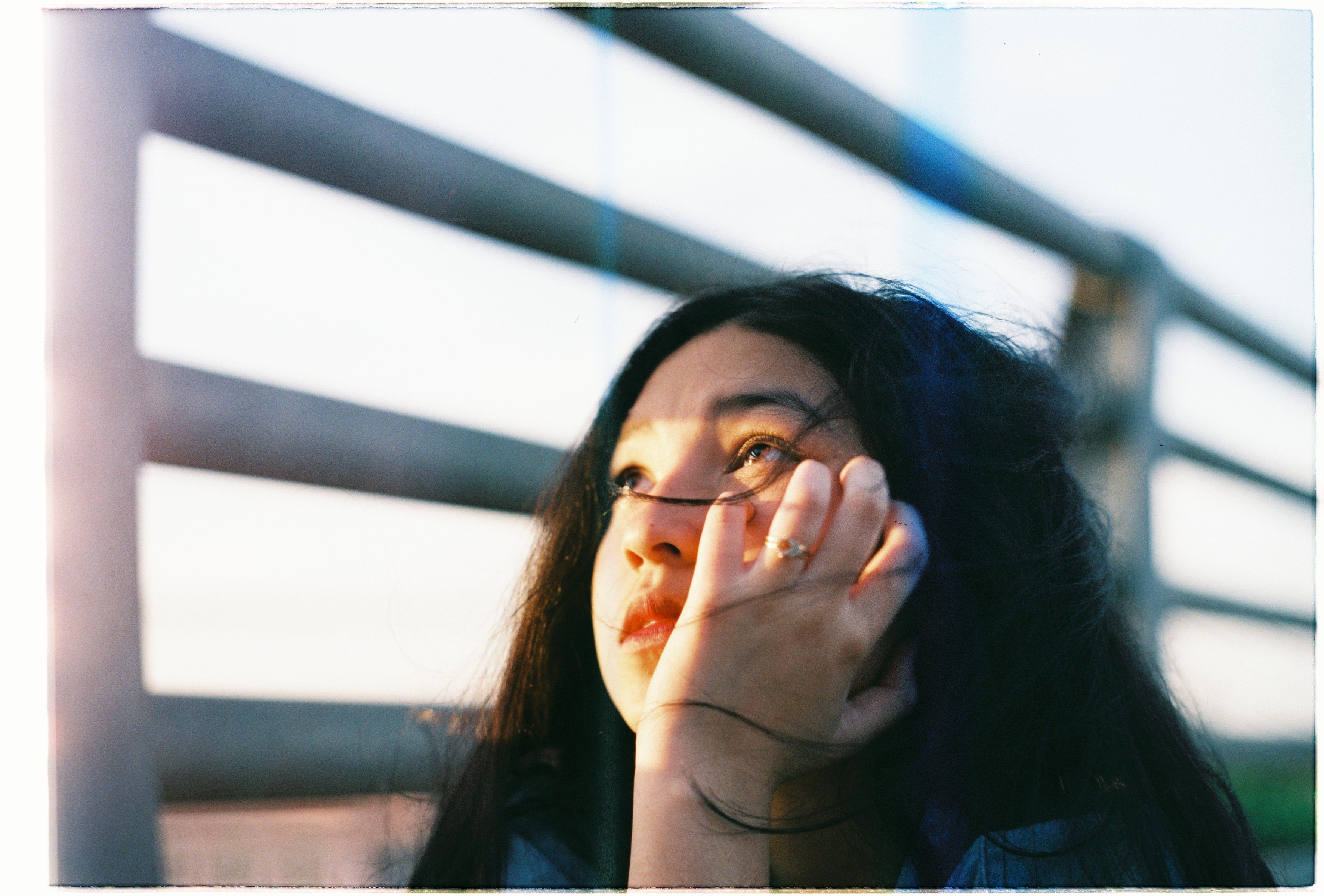 Close-up of a young woman gazing thoughtfully upwards in natural light outdoors.