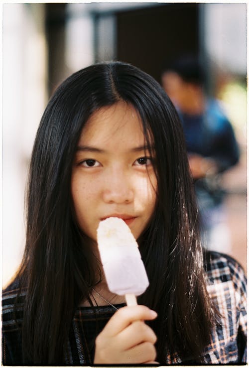 Photo of a Girl Looking at the Camera while Holding a Popsicle Stick