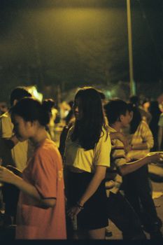 A vibrant street scene at night with diverse people enjoying a social gathering.