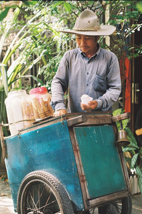Photo of a Man with a Beige Hat Selling Ice Cream