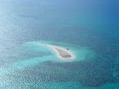 鸟瞰图中，一个被清澈绿松石海水包围的小而孤立的沙洲令人惊叹