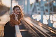 Dreamy ethnic lady leaning on fence near railroad