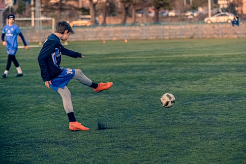 Free Photo of a Boy Kicking a Soccer Ball Stock Photo
