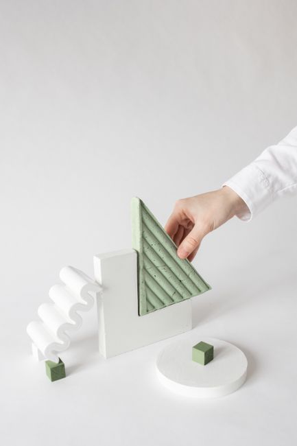 Simple composition of a hand arranging geometric shapes on white background, offering creative copy space.