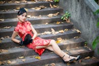 Young Asian female in stylish outfit sitting on stairs on street