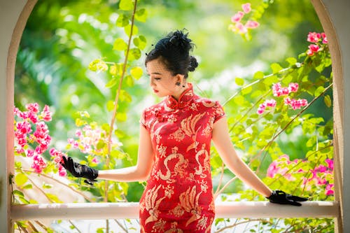 Asian woman in traditional clothes near railing and plants