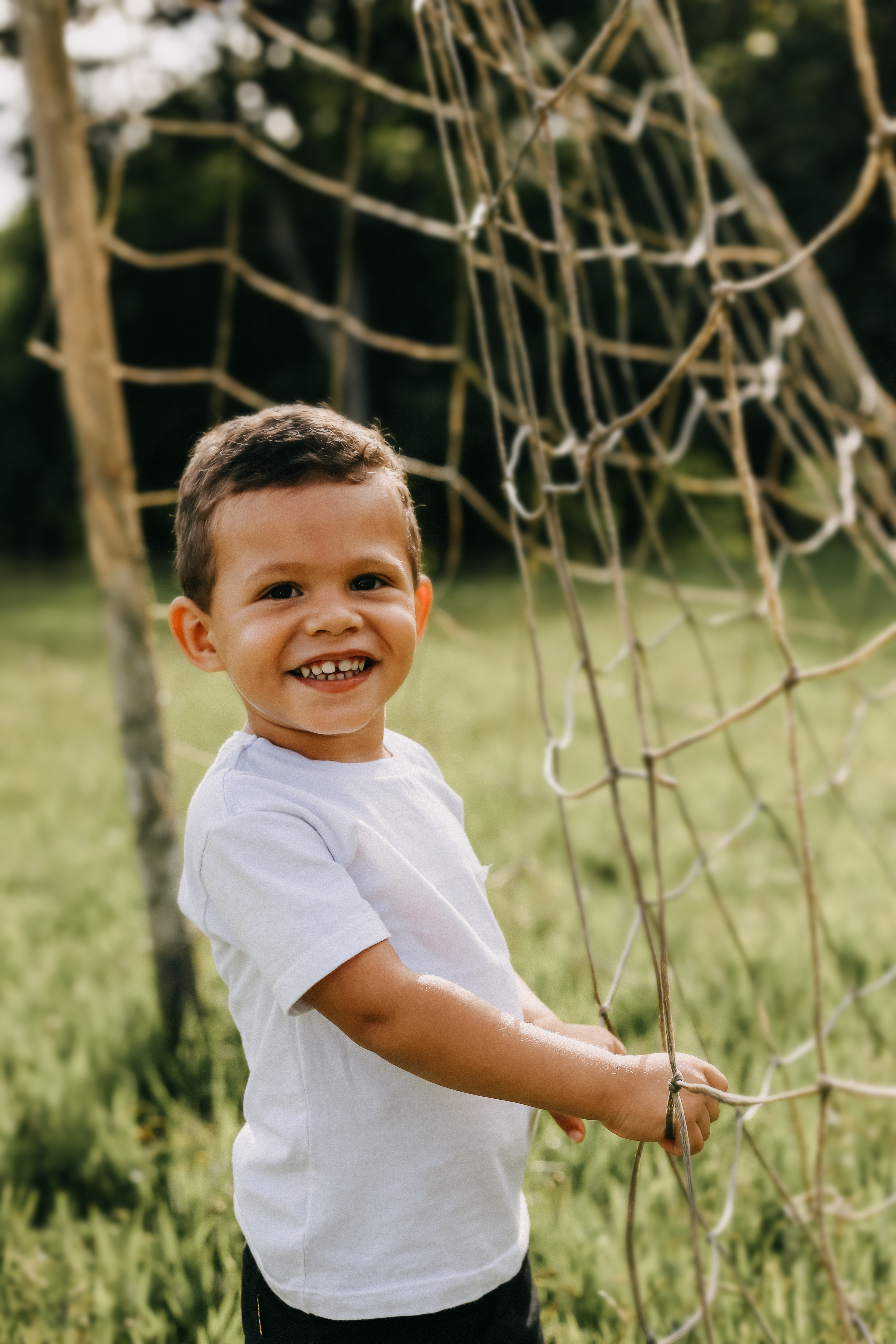 A Boy in White Shirt Holding a Net on a Grassy Field · Free Stock Photo