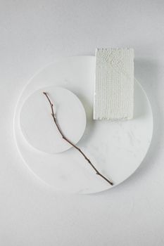 Simple minimalist design featuring a twig on geometric white objects.