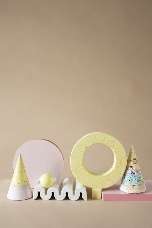 Free An artistic arrangement of colorful geometric clay shapes on a neutral background, featuring cones, rings, and spheres. Stock Photo
