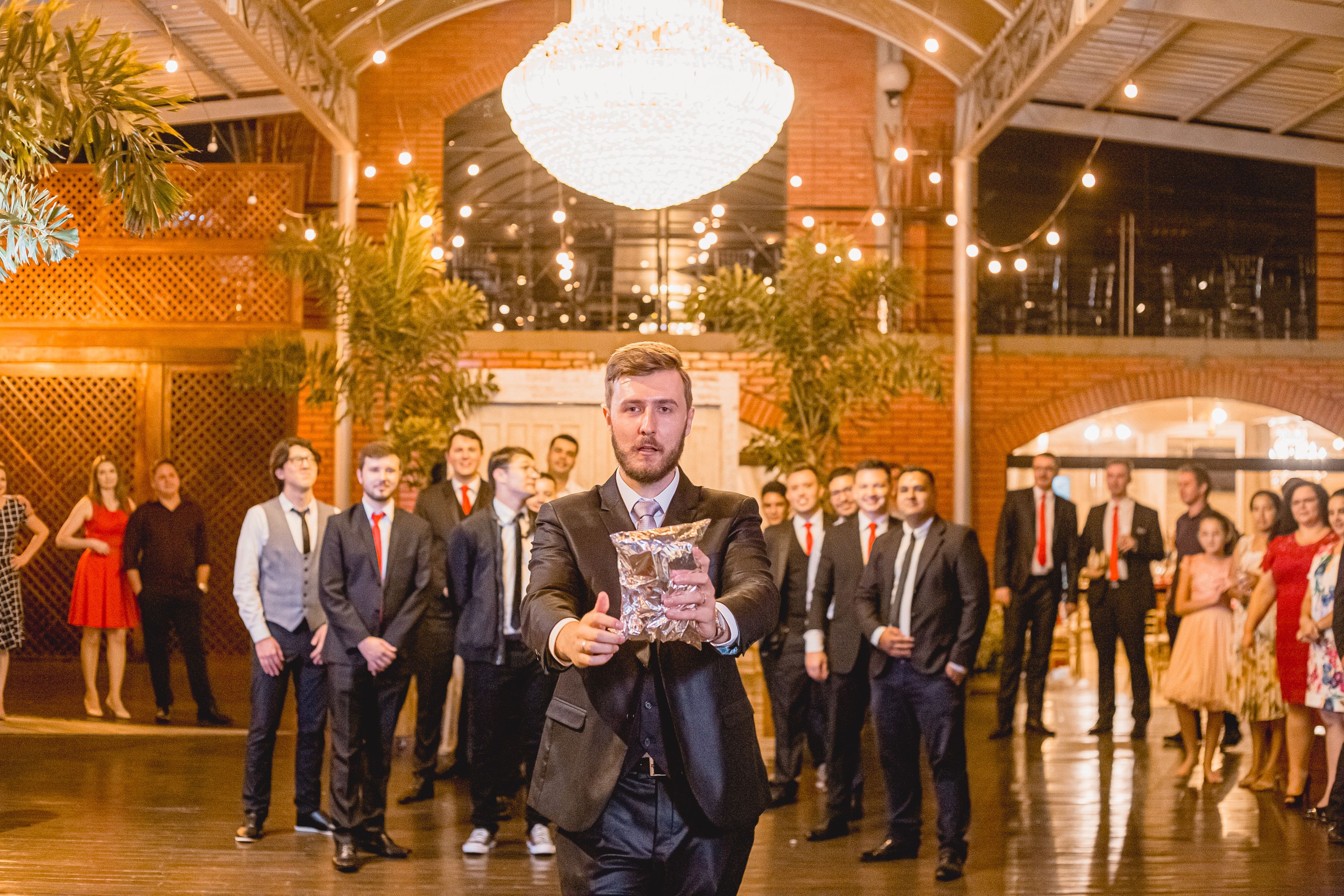 A groom prepares to toss the bouquet at a stylish indoor Brazilian wedding reception.