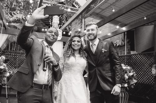 Free Black and white photo of a bride, groom, and officiant taking a joyful selfie at a wedding ceremony in Brazil. Stock Photo