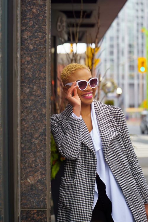 Free Trendy Black woman smiling in sunglasses and plaid coat on city sidewalk. Stock Photo