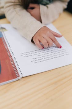 Close-up of a child's hand reading a Braille book for education.