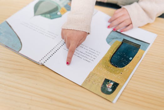 A person's finger touching braille text on an illustrated book page, focusing on learning.