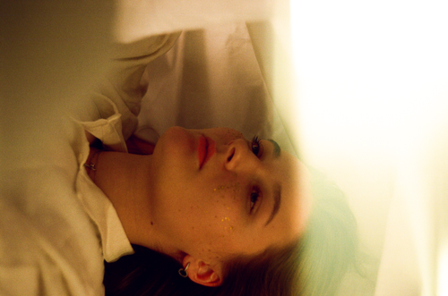 Free A thoughtful woman lying down with a serene expression in a warm, ambient light. Stock Photo