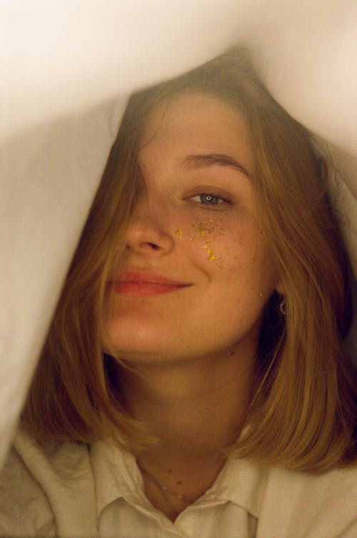 Smiling Woman with Glitter on her Face under a Blanket