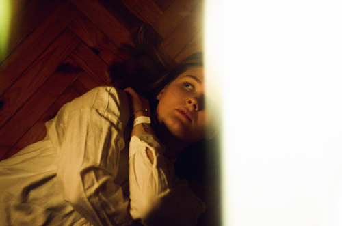 Free Artistic capture of a woman lying on a wooden floor with dramatic lighting, evoking introspective mood. Stock Photo