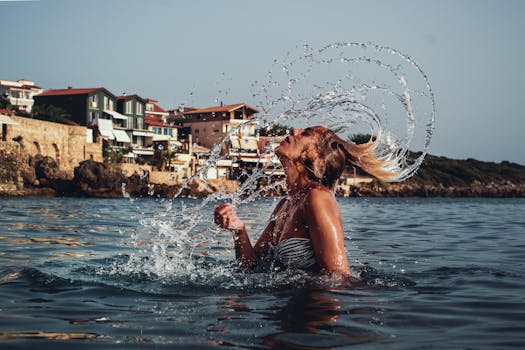 A joyful woman flips her hair while swimming in the ocean on a sunny day.