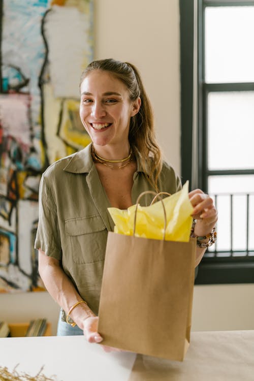 A Woman Holding a Brown Paper Bag with Yellow Wrapping Paper
