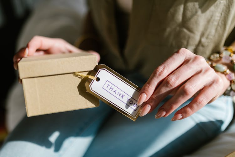 A Person Holding A Box With A Thank You Card