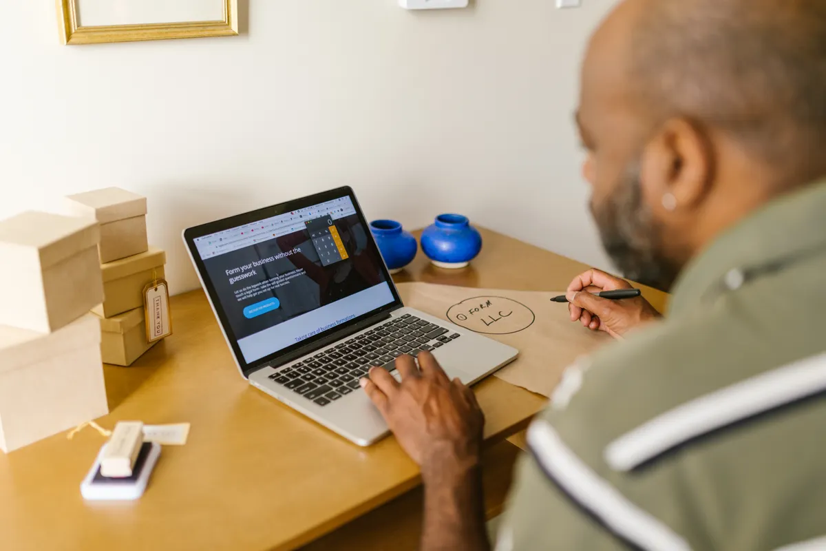 A small business owner planning at a desk with a laptop, weighing whether to do SEO in-house or hire an agency