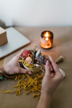 Close-up of hands creating a candle with seashells and natural elements.