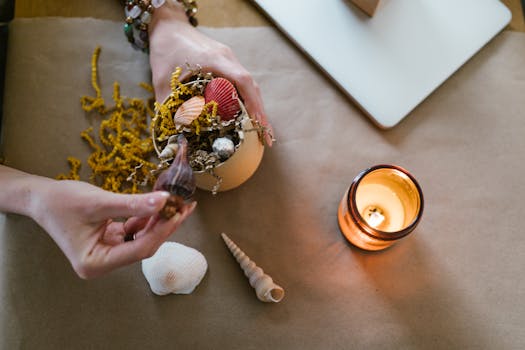 A cozy scene of hands crafting with seashells and candlelight.