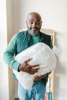 Mature man smiling and holding a bag of packing peanuts indoors, perfect for moving or recycling concepts.