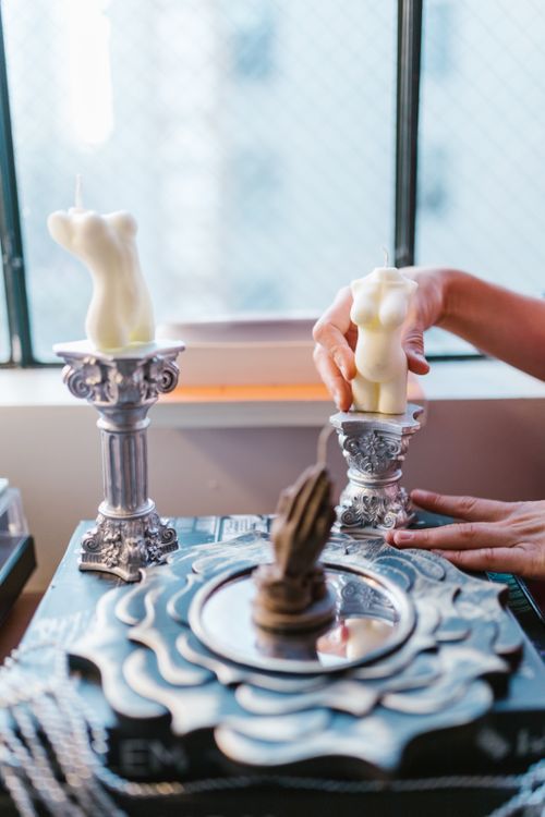 Free Close-up of hands arranging sculptural candles on ornate pedestals in a warm, creative workspace. Stock Photo