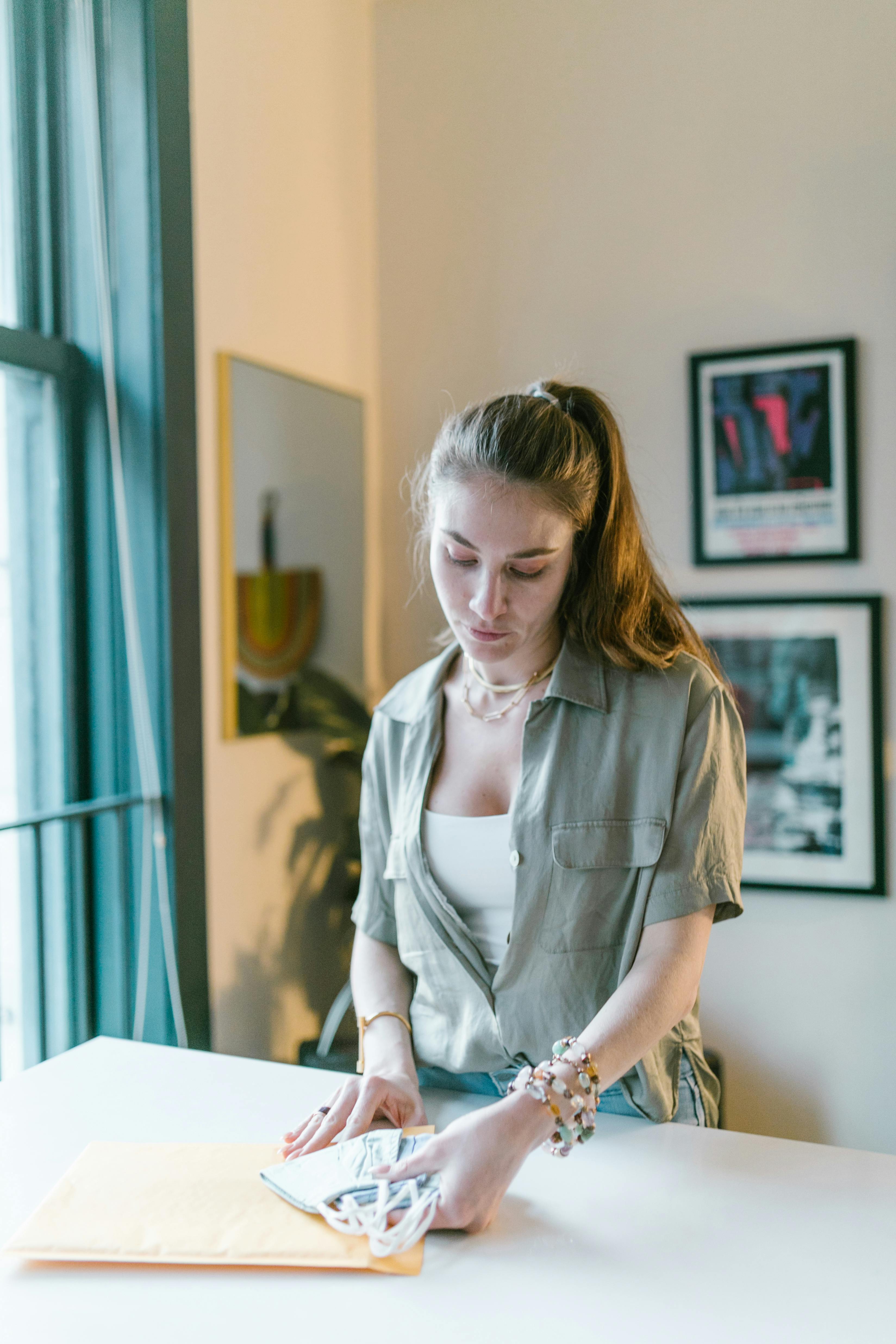 Young woman packs envelopes with face masks at home office desk.