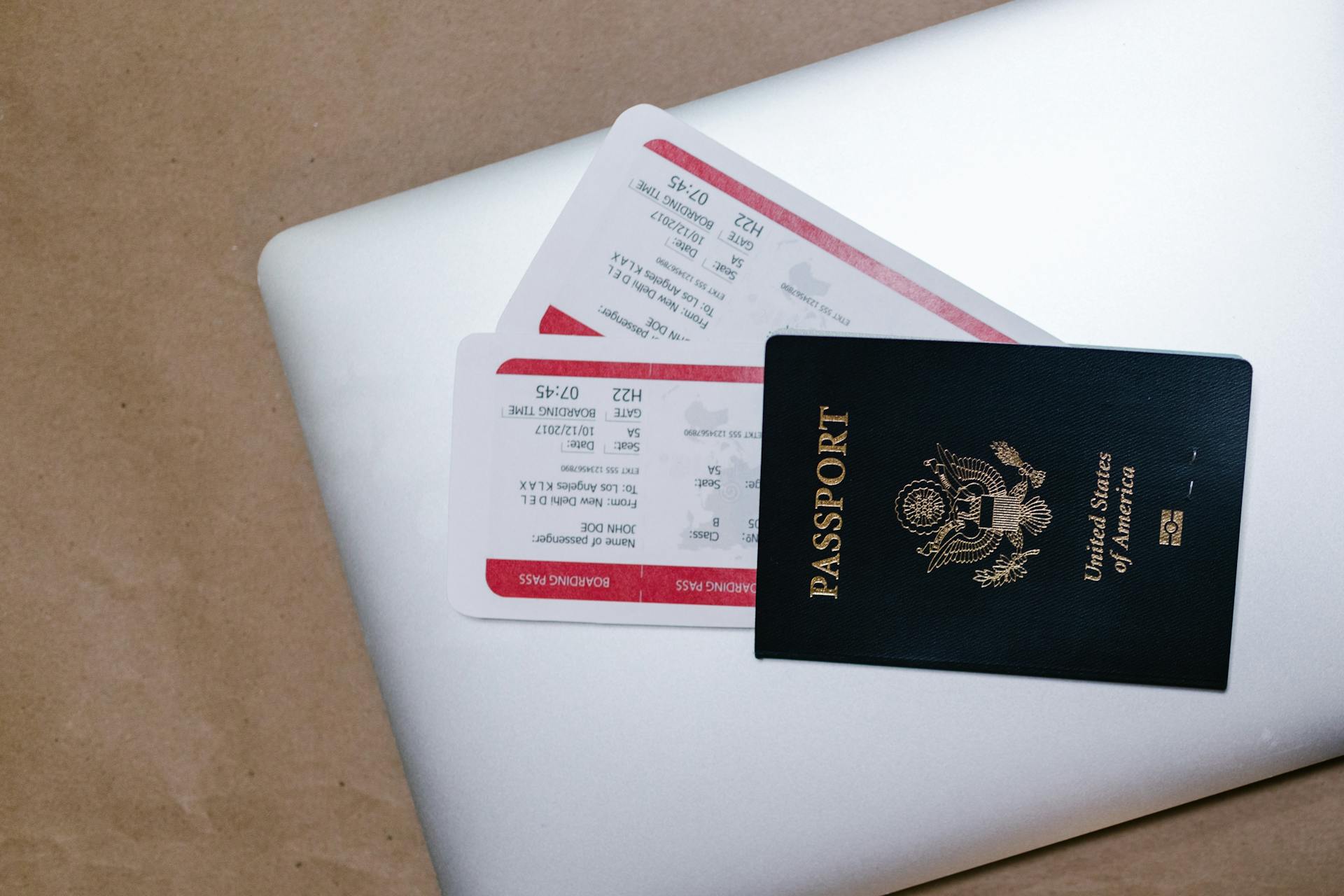 Close-up of a passport and boarding passes on a laptop, symbolizing travel preparation.