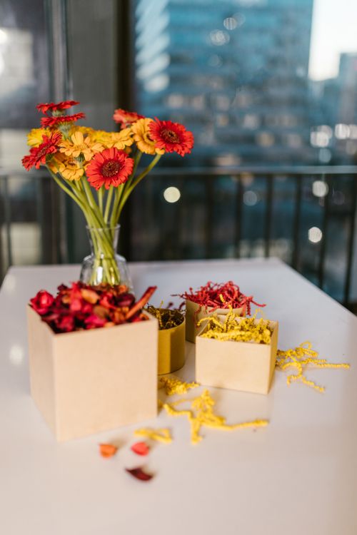 Free A colorful arrangement of flowers in a vase and decorative boxes on a table with a cityscape view. Stock Photo