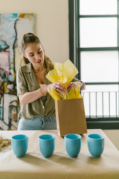 Free Woman Packing Cup into Paper Bag Stock Photo